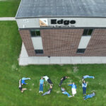 People forming the word Edge on grass